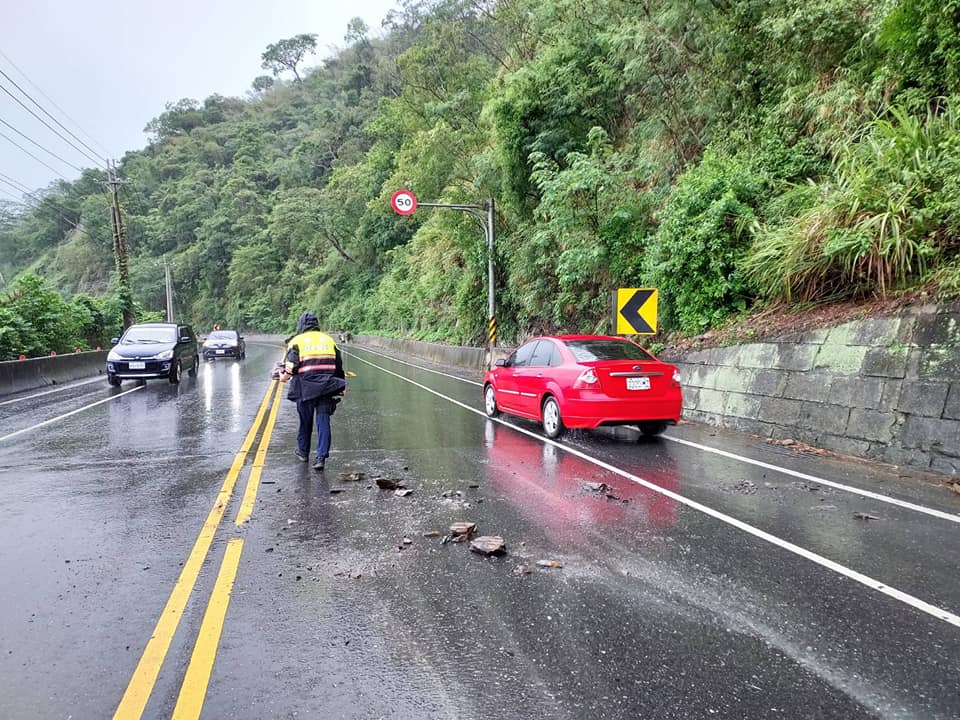 員警冒著大雨徒手合力移除路面石塊，讓交通恢復順暢。